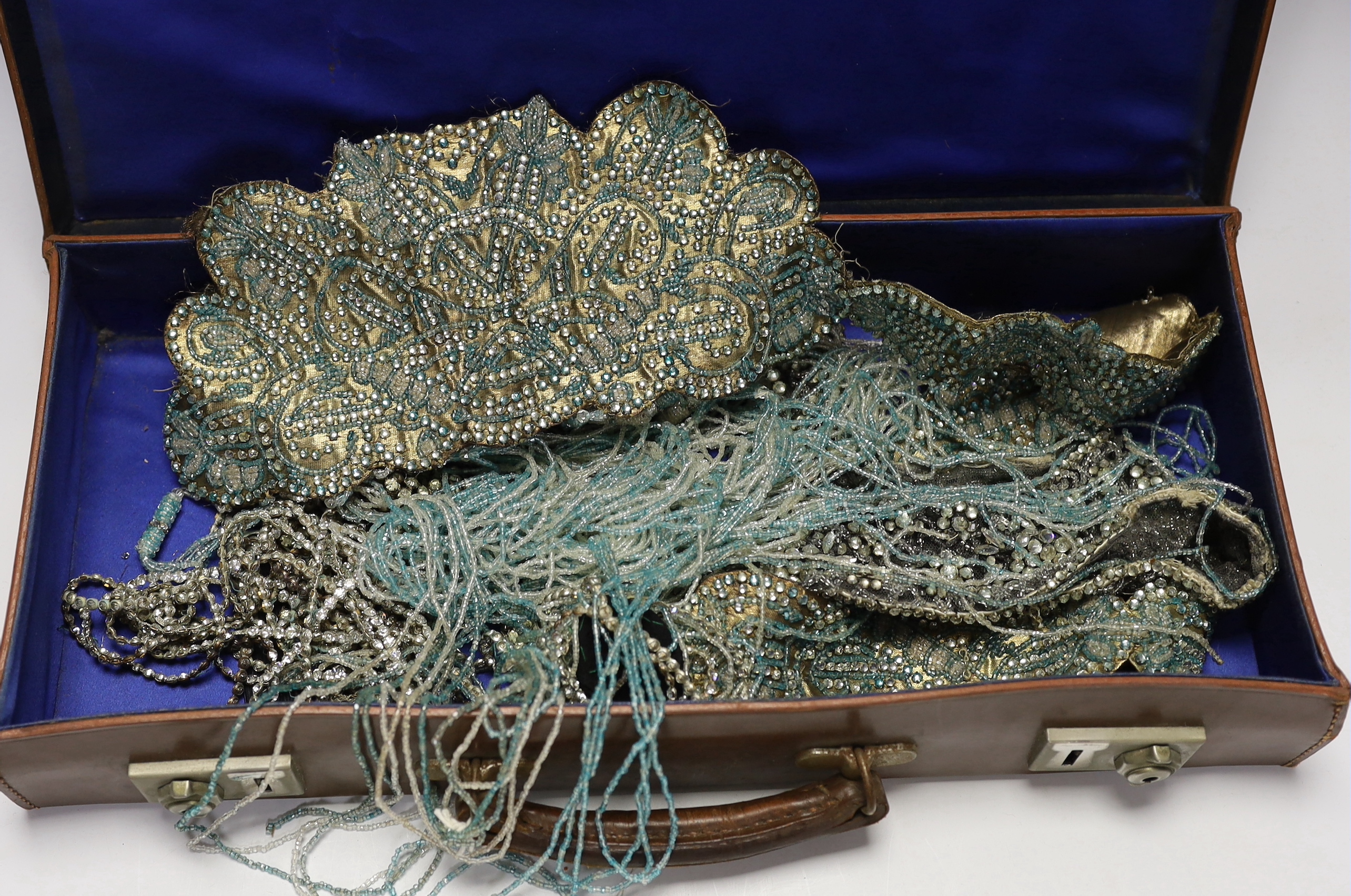 A 1920’s flapper coloured beaded and fringed appliqués and a diamanté appliquéd hat in a small leather case